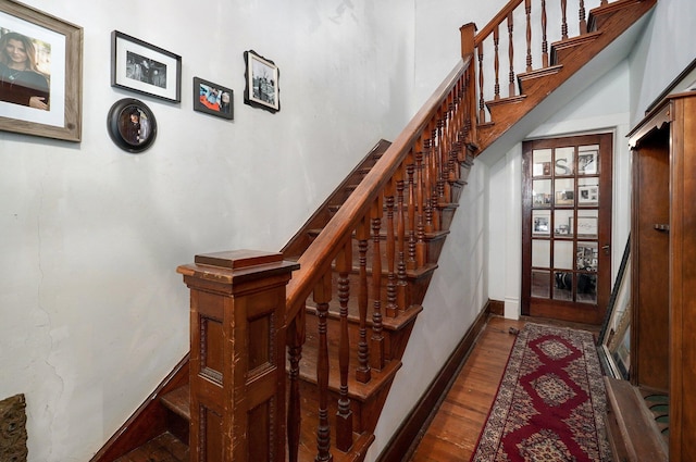 staircase featuring hardwood / wood-style floors and a towering ceiling