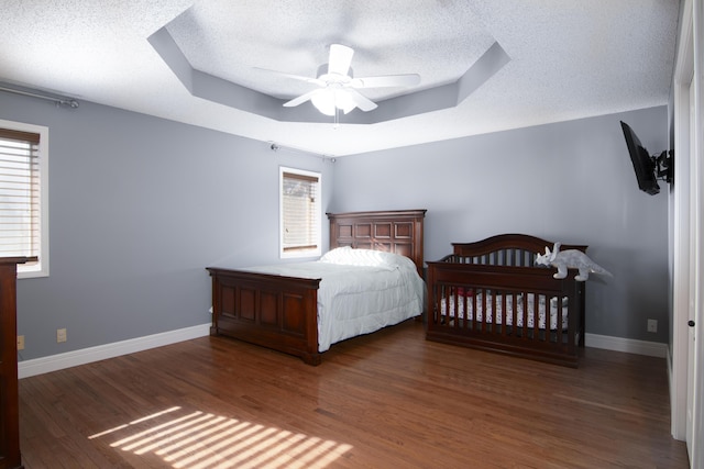 1012 W Monarch Dr, Nixa, MO 65714 - bedroom featuring a raised ceiling, a textured ceiling, multiple windows, wood finished floors, and a ceiling fan