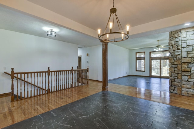 empty room featuring ceiling fan with notable chandelier and dark hardwood / wood-style flooring