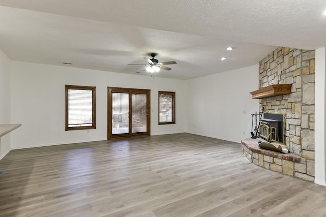 unfurnished living room featuring ceiling fan, light hardwood / wood-style flooring, and a textured ceiling