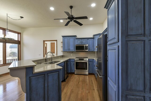 kitchen featuring blue cabinets, sink, ceiling fan, kitchen peninsula, and stainless steel appliances