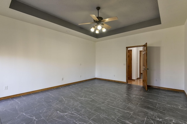 spare room featuring a tray ceiling and ceiling fan