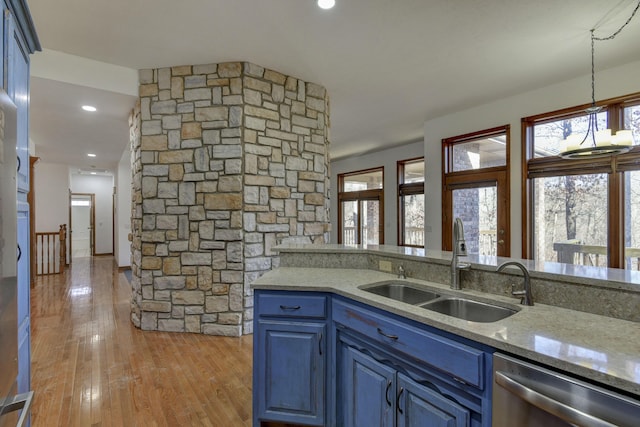 kitchen with blue cabinetry, light stone counters, dishwasher, and sink