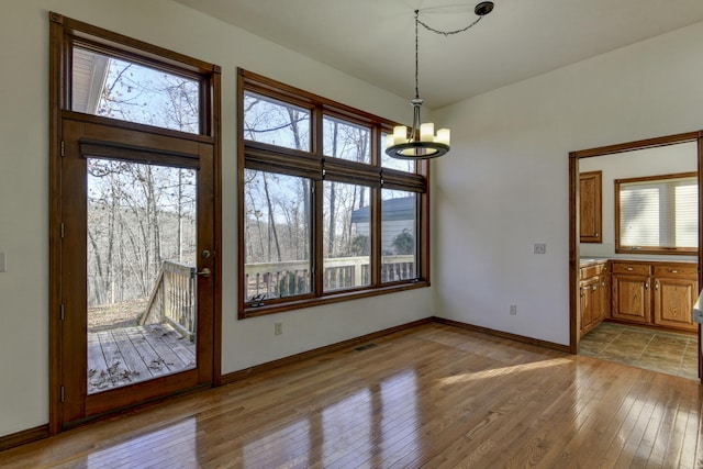 unfurnished dining area featuring light hardwood / wood-style flooring and a notable chandelier