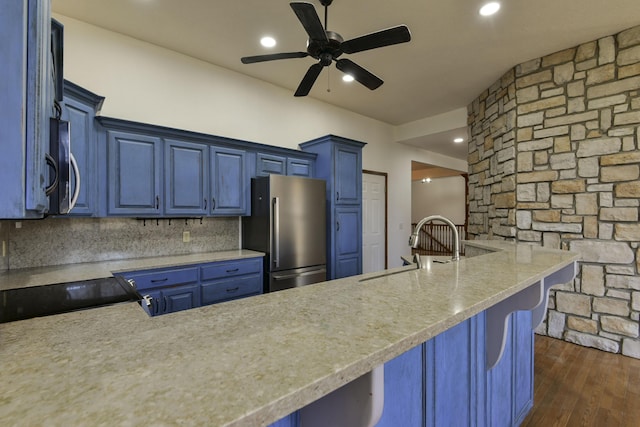 kitchen featuring kitchen peninsula, stainless steel appliances, and blue cabinets