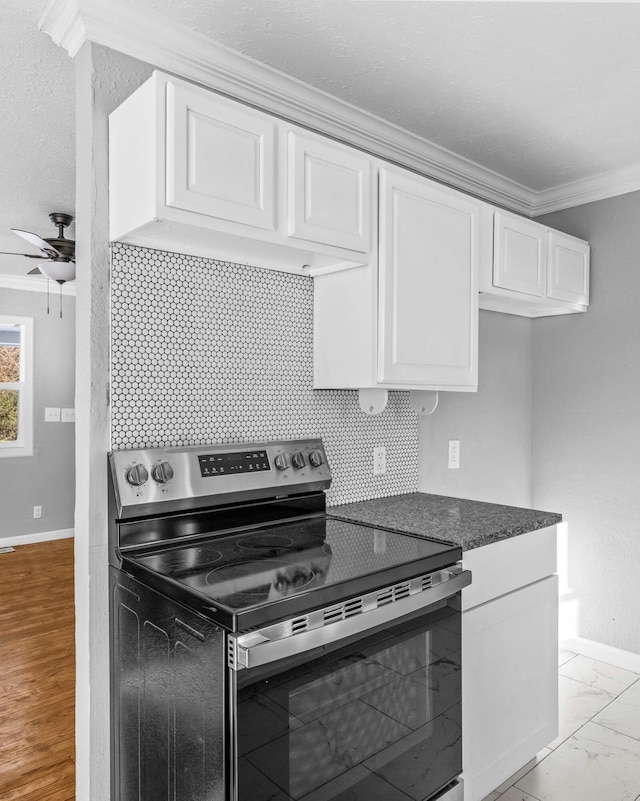 kitchen featuring white cabinets, ornamental molding, ceiling fan, tasteful backsplash, and stainless steel electric range