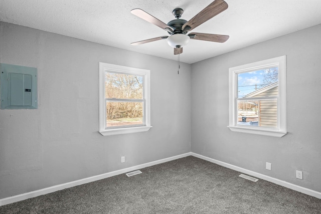 carpeted spare room with electric panel, a textured ceiling, and ceiling fan