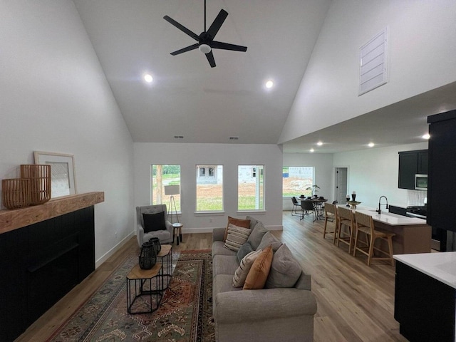 living room with ceiling fan, wood-type flooring, and high vaulted ceiling