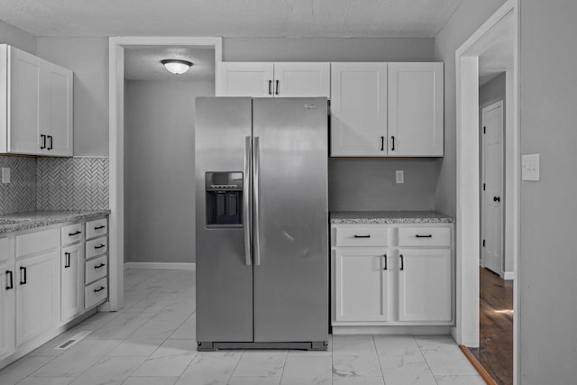 kitchen with white cabinets, stainless steel fridge with ice dispenser, and decorative backsplash