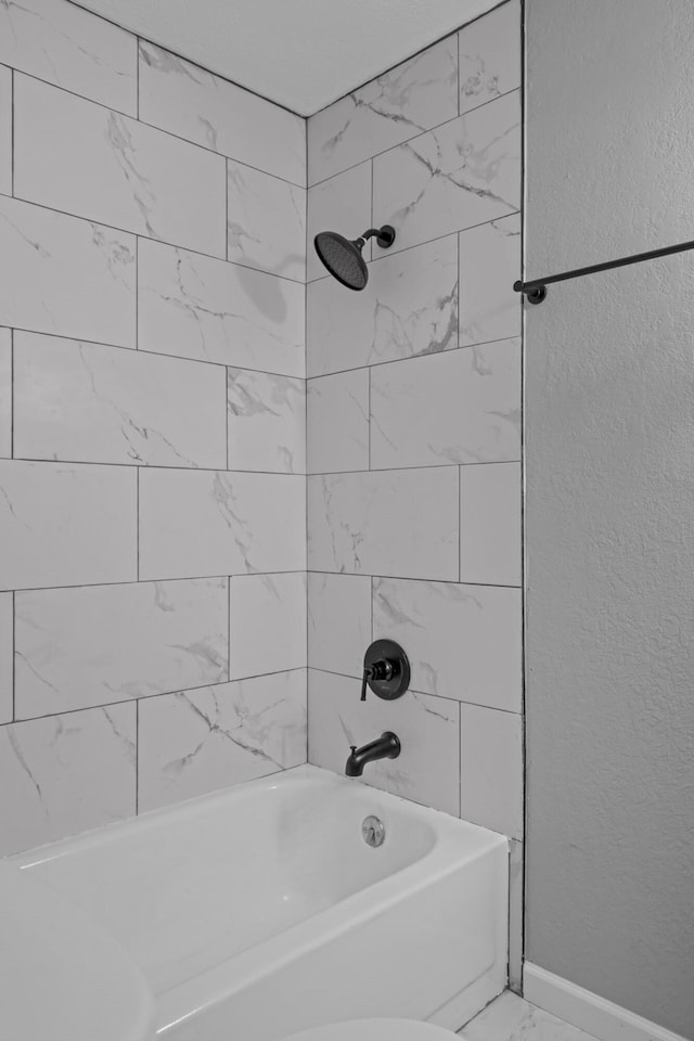 bathroom with toilet and tiled shower / bath combo