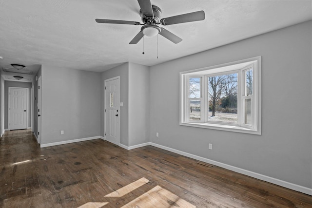 empty room with dark wood-type flooring and ceiling fan