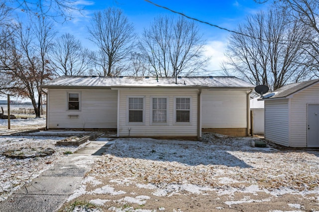 snow covered back of property featuring a shed