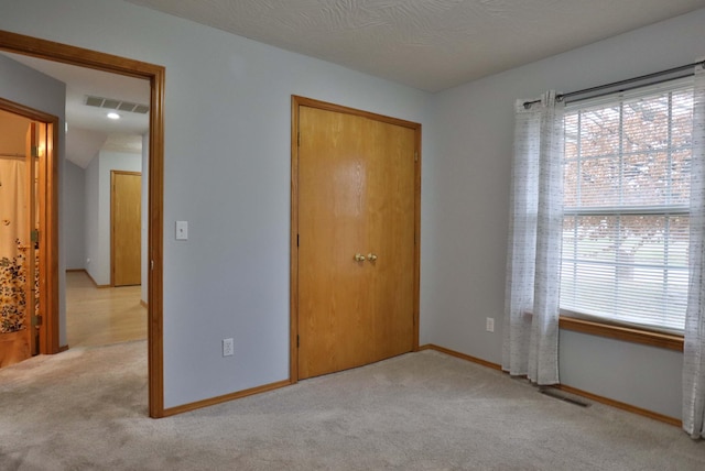 unfurnished bedroom featuring light carpet and a closet