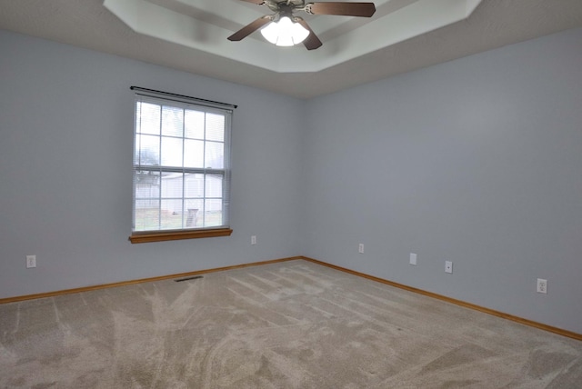 carpeted spare room featuring ceiling fan and a tray ceiling