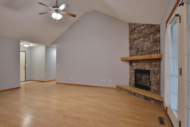 unfurnished living room with ceiling fan, light hardwood / wood-style floors, a stone fireplace, and lofted ceiling