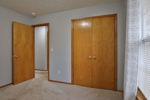 unfurnished bedroom with light colored carpet and a closet