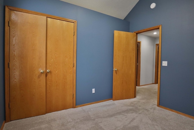 unfurnished bedroom featuring vaulted ceiling, light carpet, and a closet