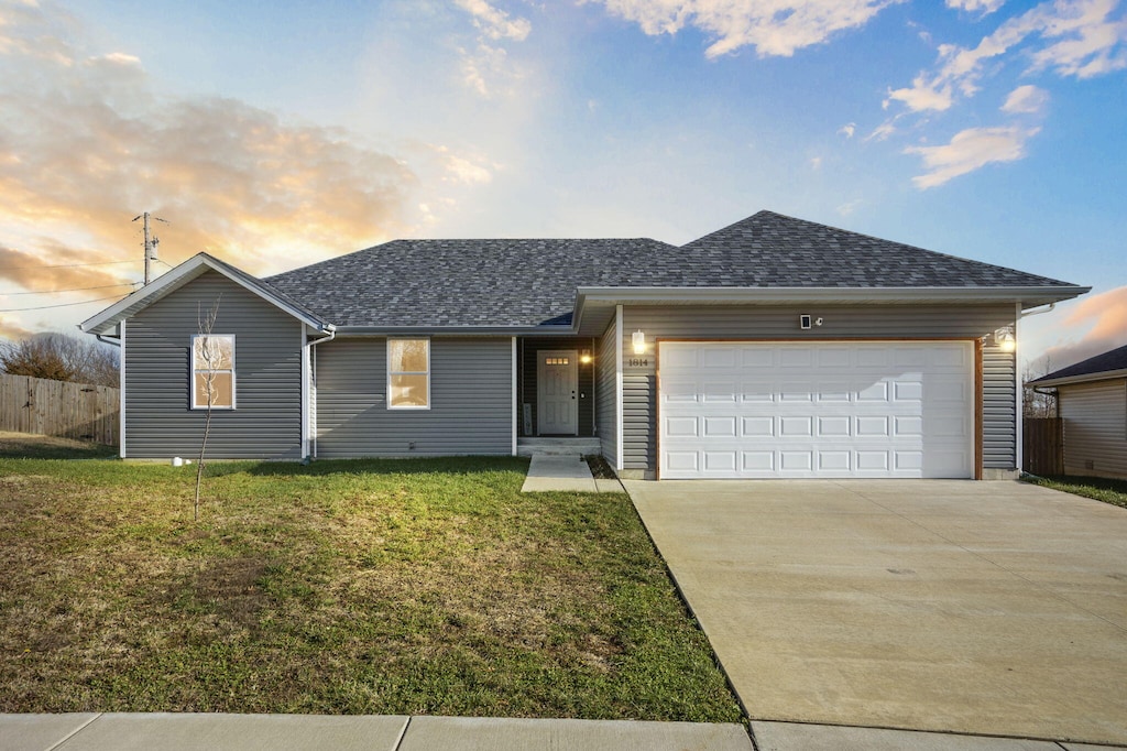 ranch-style home featuring a garage and a yard