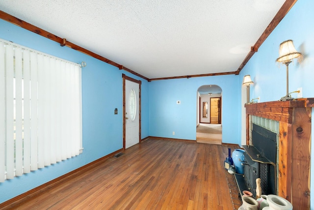 unfurnished living room featuring ornamental molding, plenty of natural light, and dark wood-type flooring