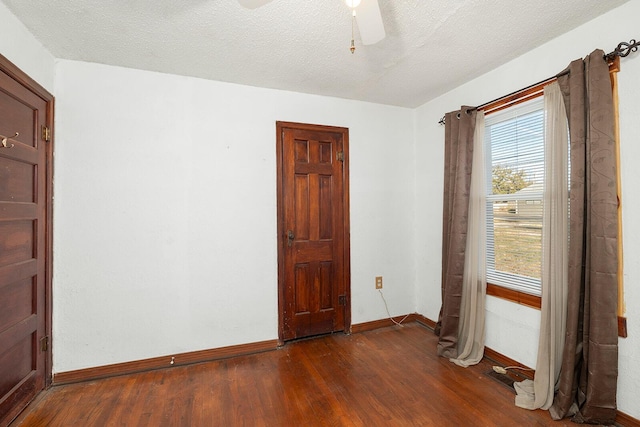 unfurnished room featuring ceiling fan, dark hardwood / wood-style flooring, and a textured ceiling