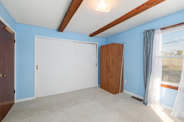 bedroom featuring a textured ceiling, light colored carpet, and a closet