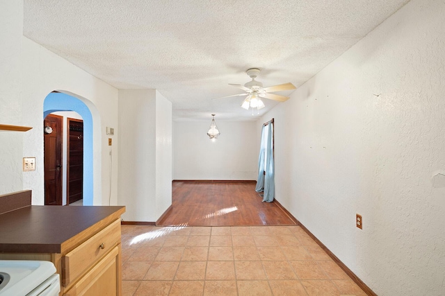 empty room featuring light tile patterned floors, a textured ceiling, and ceiling fan