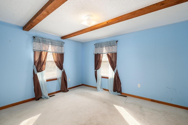 carpeted empty room featuring beam ceiling and a textured ceiling