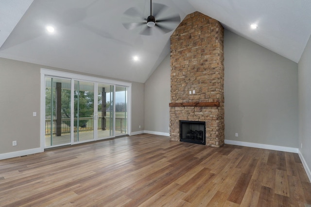 unfurnished living room featuring high vaulted ceiling, light hardwood / wood-style floors, a stone fireplace, and ceiling fan