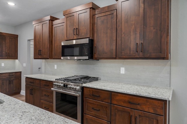 kitchen with tasteful backsplash, light stone counters, and stainless steel appliances