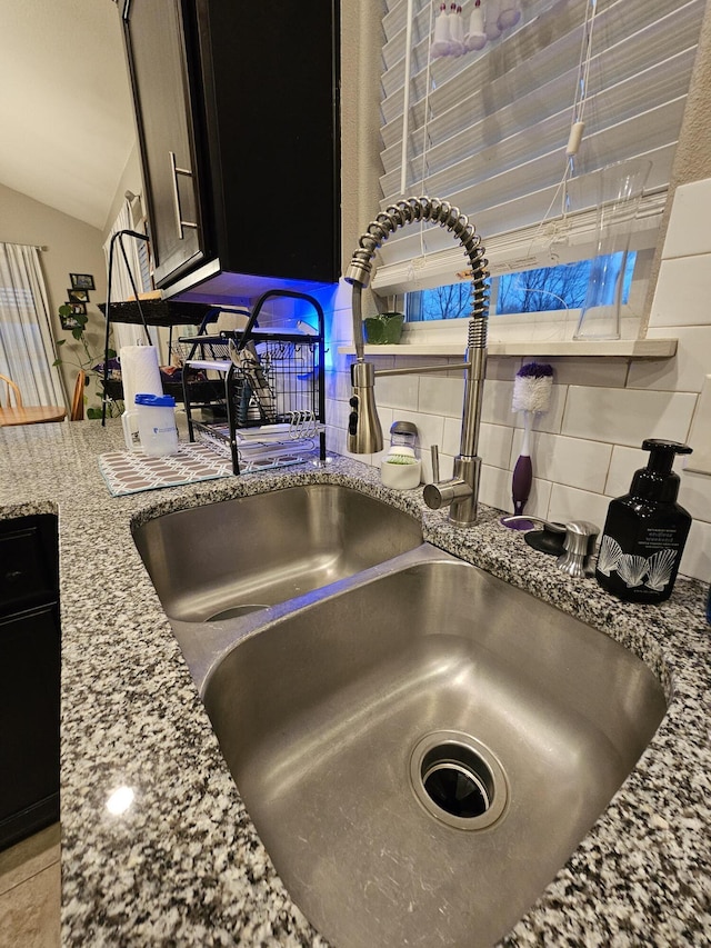 room details with backsplash, light stone counters, and sink