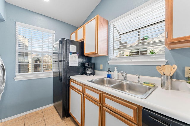 kitchen featuring dishwasher, sink, lofted ceiling, black refrigerator, and light tile patterned flooring