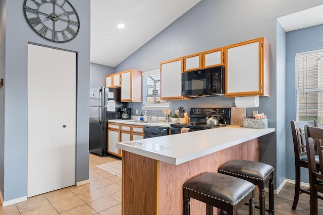 kitchen with sink, kitchen peninsula, vaulted ceiling, a breakfast bar area, and black appliances