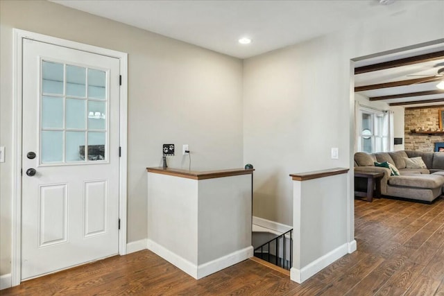 interior space featuring beam ceiling, a stone fireplace, ceiling fan, and dark hardwood / wood-style flooring