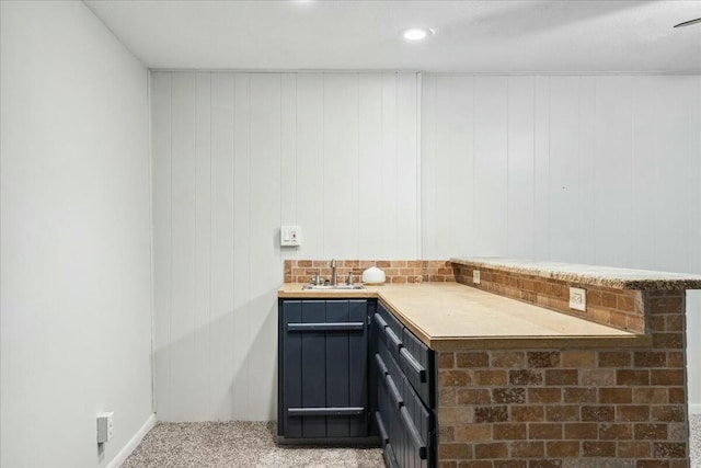 bar featuring wood walls, sink, and light colored carpet