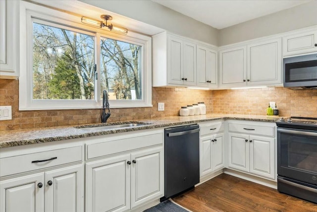 kitchen with white cabinetry, sink, light stone counters, dark hardwood / wood-style flooring, and appliances with stainless steel finishes