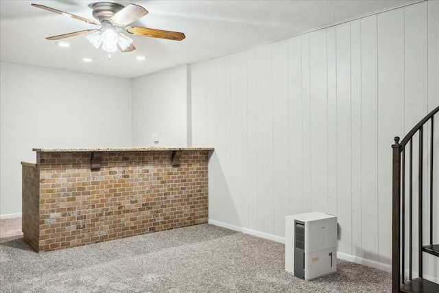 bar featuring ceiling fan, carpet floors, a textured ceiling, and wooden walls