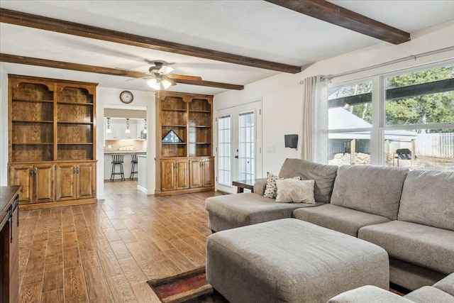 living room featuring beamed ceiling, ceiling fan, a healthy amount of sunlight, and french doors