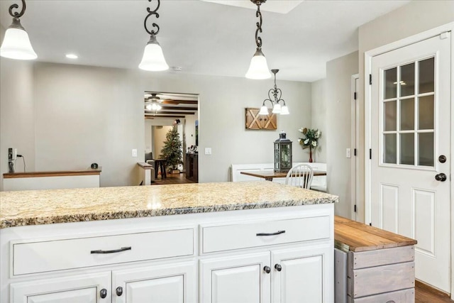 kitchen featuring pendant lighting, light stone counters, and white cabinetry