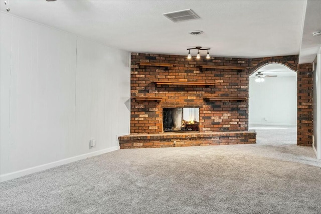 unfurnished living room featuring ceiling fan, carpet floors, and a fireplace