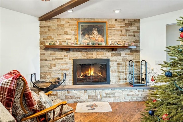 living room featuring beam ceiling, a stone fireplace, and hardwood / wood-style floors