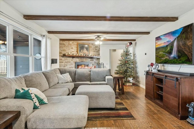 living room with beamed ceiling, ceiling fan, hardwood / wood-style flooring, and a brick fireplace