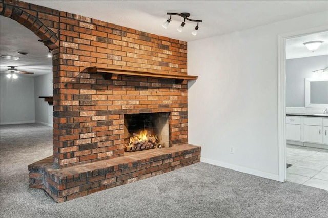 unfurnished living room with light carpet, a brick fireplace, ceiling fan, and sink