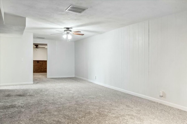 carpeted empty room featuring wood walls