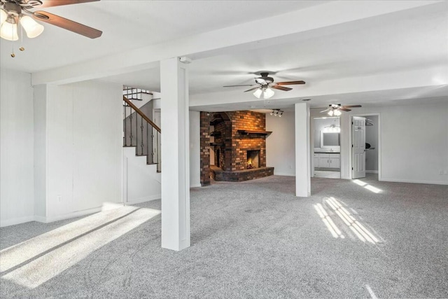 unfurnished living room with ceiling fan, carpet floors, and a brick fireplace