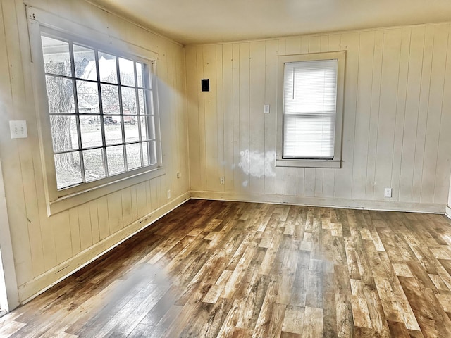 spare room featuring dark hardwood / wood-style flooring and wooden walls