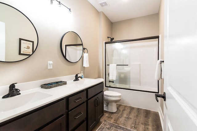 full bathroom featuring hardwood / wood-style floors, toilet, combined bath / shower with glass door, and vanity