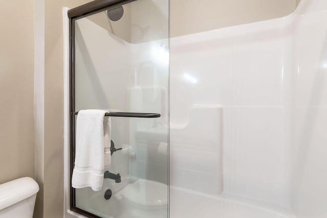 bathroom featuring a shower with shower door and toilet