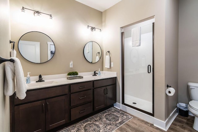 bathroom with a shower with door, vanity, wood-type flooring, and toilet