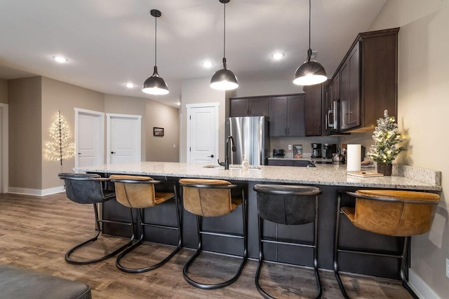 kitchen with dark hardwood / wood-style flooring, dark brown cabinets, stainless steel appliances, sink, and decorative light fixtures