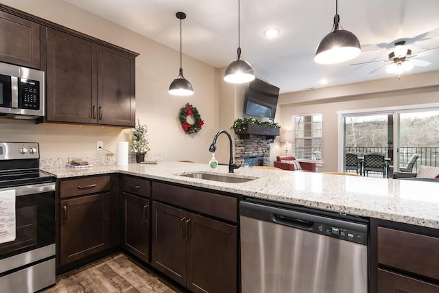 kitchen with dark brown cabinetry, stainless steel appliances, sink, light hardwood / wood-style floors, and hanging light fixtures